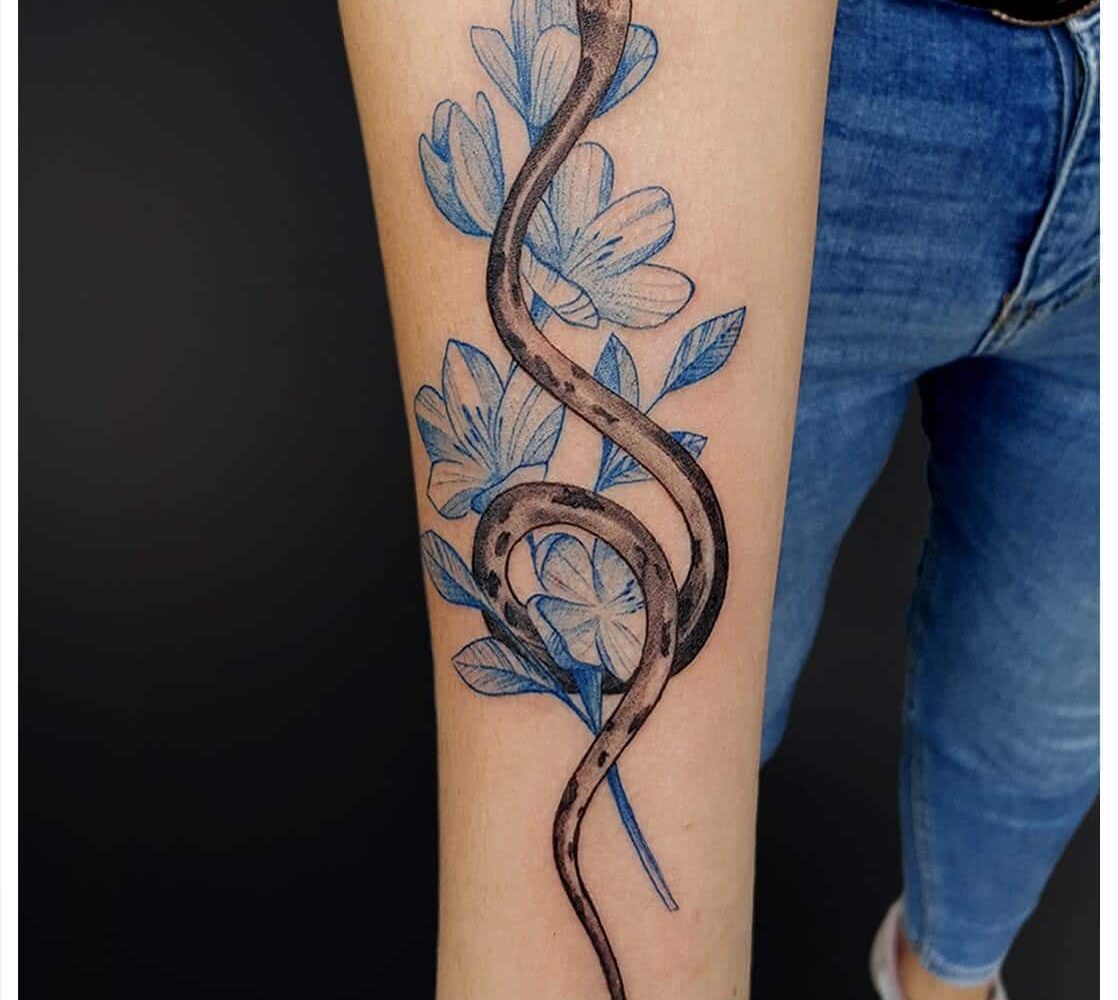 Tatuaż damski wąż z motywem roślinnym na przedramieniu
