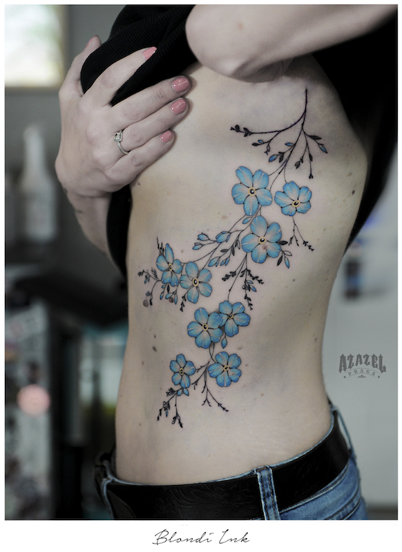 Tatuaż damski na żebrach z niebieskimi kwiatami