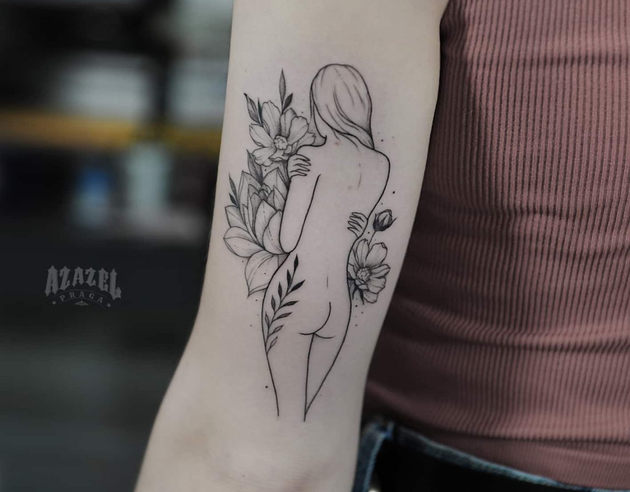 Minimalistyczny tatuaż kobieta odwrócona tyłem na ramieniu